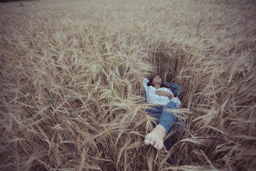 Naklejka na ściany i meble Dreaming in a wheaten field beautiful young adult woman
