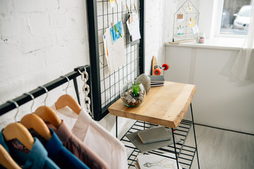 Pinboards with drawings, straight rack and wooden table in teenage room
