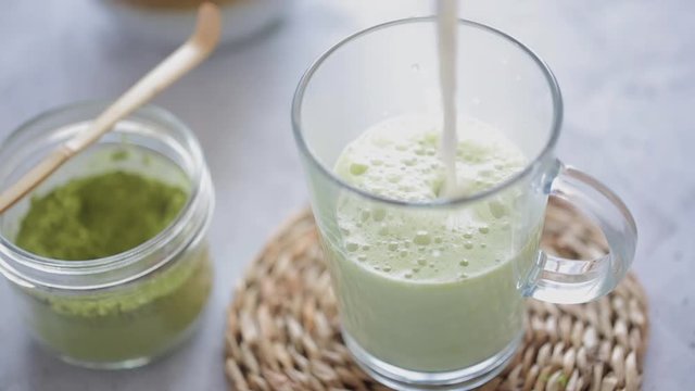 Man mixing green tea matcha in a bowl on blue surface. Drink is a rich source of antioxidants and polyphenols 