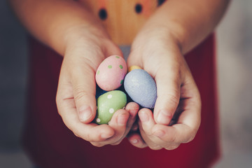 Little girl hands holding easter eggs painted color on hand
