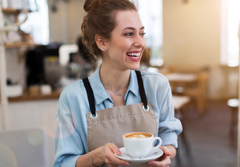 Woman in cafe with cup of coffee in her hands