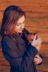 Young Girl Holding A Little Dog Over Wooden Background. Owner And Pet.  Pretty Young Caucasian Girl And Dog. People, Animals Concept.