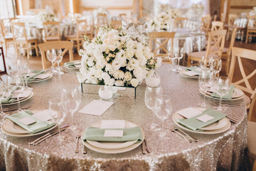 on the banquet table are plates, cutlery, glasses and flower arrangements