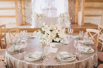 on the banquet table are plates, cutlery, glasses and flower arrangements