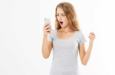 Angry teen woman in grey shirt shouting on smartphone over white background, bad news reading
