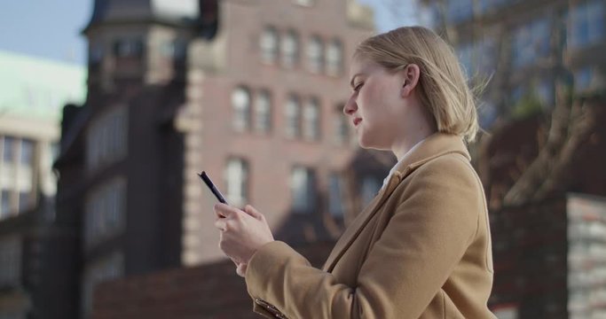 Beautiful woman standing outside in the city using her tablet