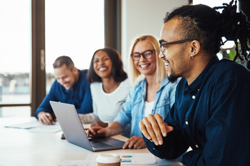 Young African American businessman laughing with coworkers durin