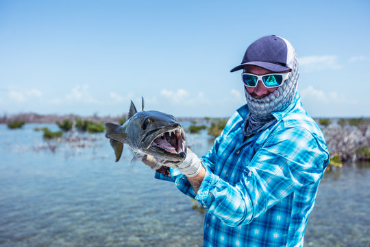 Fly fisherman holding a barracuda for a photo before releasing it. Cuba