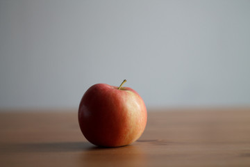 one red Apple on a wooden table on a light background