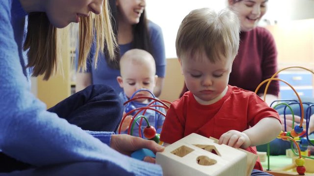 Group Of Mothers And Toddlers Playing With Toys At Playgroup