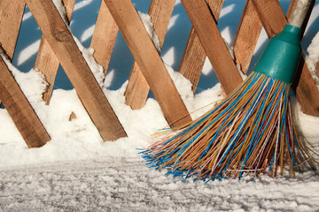 A plastic broom with multicolored bristles of the pile stands in the snow. The concept of cleaning ...