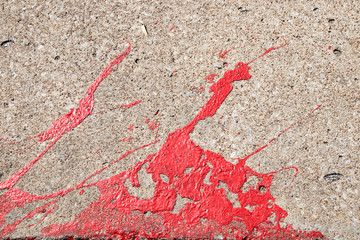 Background of very textured concrete with red paint spilled and splattered across it - grunge