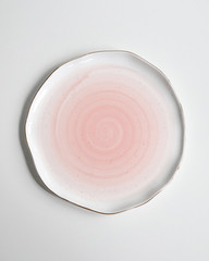 New luxury cutlery view from above on a isolated white background. Top view. Porcelain pink saucer with gold ring. Trendy Coral plate tones. Flat lay view.