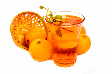 Raw organic orange in a basket and its extracted fresh organic juice in a transparent glass along with some mint or mentha leaves as decoration isolated on white with reflection also.