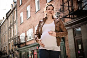 Pregnant girl outside on a city background