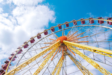 Beautiful ferris wheel on the background of blue sky with clouds