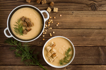 pea soup with croutons and greens on a wooden background