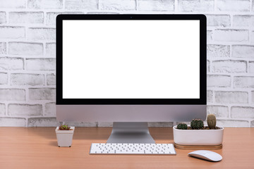Blank screen of All in one Computer with cactus pots on wooden table, White brick wall background