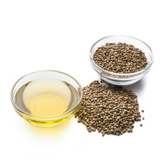 Hemp oil and seeds in bowls on white