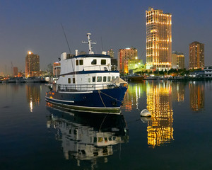 Night scenery of a ship docking at Manila Bay near Manila Yacht Club with illuminated high-rise buildings in the background reflecting in the water