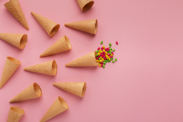 Waffle cones and sprinkles on pink surface