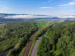 Fototapeta na wymiar aerial view road with railway station in mountains with forest