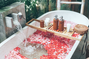 Cosmetic products on bath tub with flowers