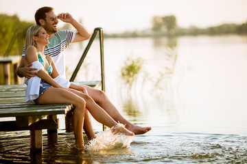 Loving couple sitting on the pier on lake