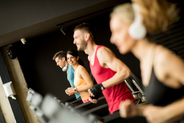 young people running on treadmills in modern gym