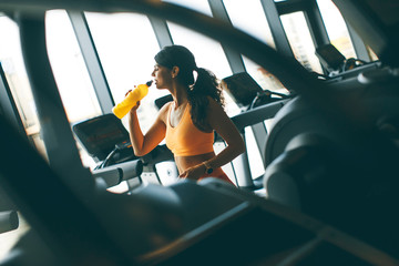 Naklejka premium Young women in yellow sport shirt are drinking water at the gym