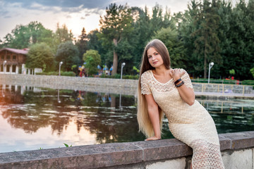Woman posing in dress before lake in modern city