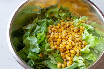 Iceberg lettuce and sweet corn in metal bowl