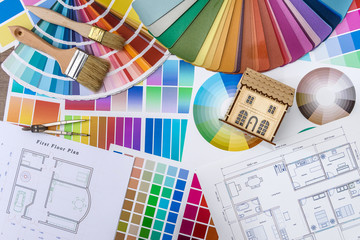 Close up of wooden house model with blueprint and color swatches