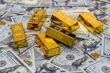 Gold bars with hundred dollar banknotes as background