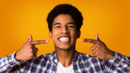 Perfect smile. Guy showing and pointing fingers on teeth