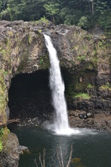 Rainbow Falls Downtown Hilo Hawaii Waterfall cascading down a rocky alcove into a pool surrounded by jungle