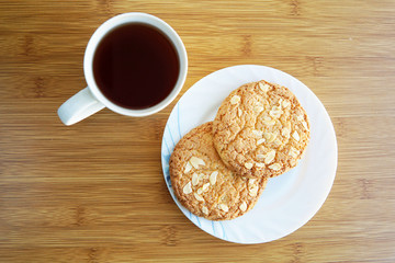Cup of tea and saucer with cookies with nuts on the table. Top view.