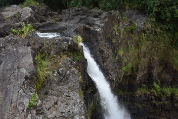 Rainbow Falls Downtown Hilo Hawaii Waterfall cascading down a rocky alcove into a pool surrounded by jungle