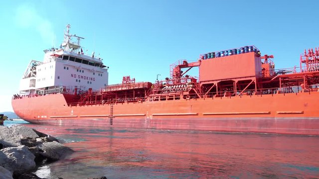 Cargo ship enters the Corinth Canal from the Gulf of Corinth over the submersible bridge. Beautiful scenery of the Corinth Canal against the blue sky and mountains in a bright sunny day