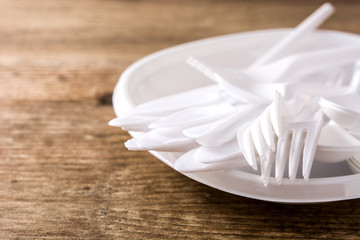Disposable plastic crockery on wooden background. Copyspace