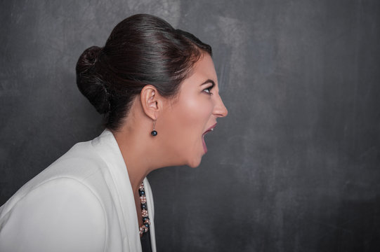 Angry screaming woman on chalkboard background. Side view