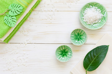 Green plant leaf, aromatic sea salt and towels. Concept for spa, beauty and health salons. Close up photo on white wooden background, top view