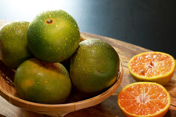 Closeup tangerines or clementines or oranges, in wooden basket on wooden table background. Fruits concept.