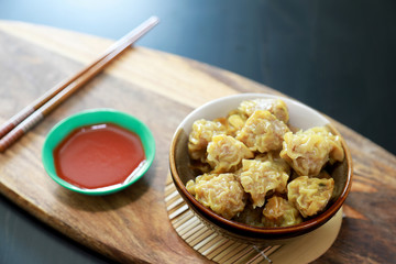 Steamed dumpling Pork Chop Dim Sum in the bowl with sauce in the cups on the wooden table background, Foods concept.