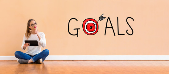 Goals with target with young woman holding a tablet computer