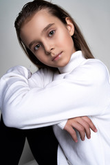 Portrait of a cute teen girl wearing a white turtleneck sweater. Isolated on gray background. Advertising, trendy and commercial design. Copy space
