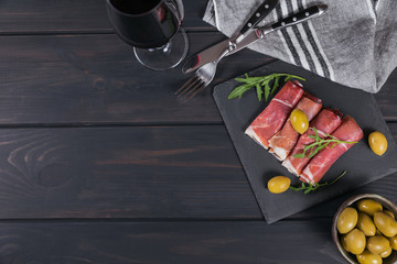 Black stone platter with slices of cured ham or Spanish jamon serrano or Italian prosciutto crudo