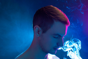 man on a blue background exhales smoke
