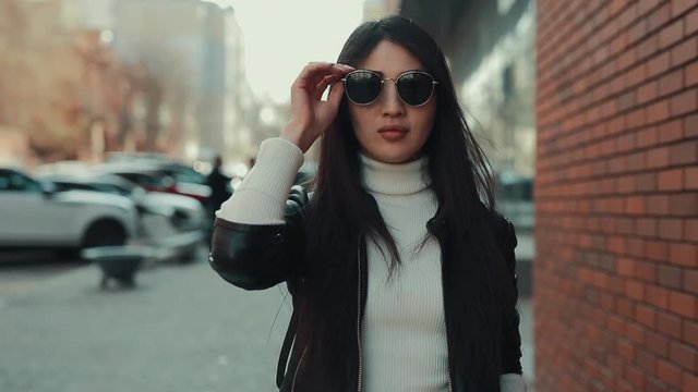 Asian woman walks along city street in eyewear