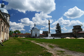 The stone walls of the ancient castle on a background of blue sky and the spring landscape